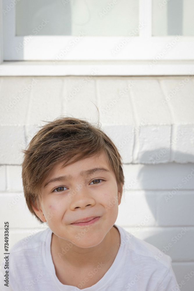 Portrait of boy sitting against white brick wall Portrait of boy sitting against white brick wall