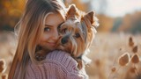 A young beautiful woman gently hugs her Yorkshire terrier dog