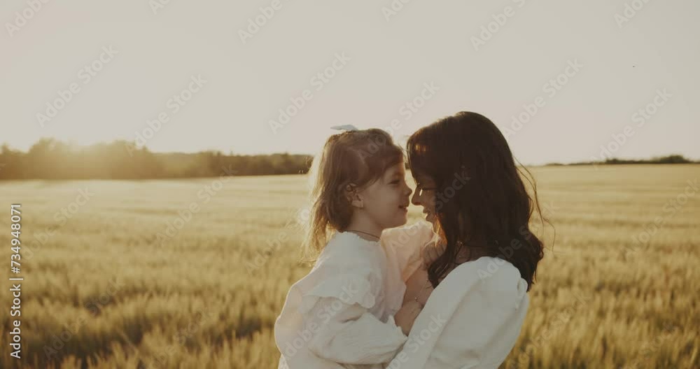 young mother and daughter together happily walking on sunny wheat meadow hugging smiling. mother carries her daughter in arms, gently presses to her and kisses. Future of Ukraine. calm Peaceful life young mother and daughter together happily walking on sunny wheat meadow hugging smiling. mother carries her daughter in arms, gently presses to her and kisses. Future of Ukraine. calm Peaceful life