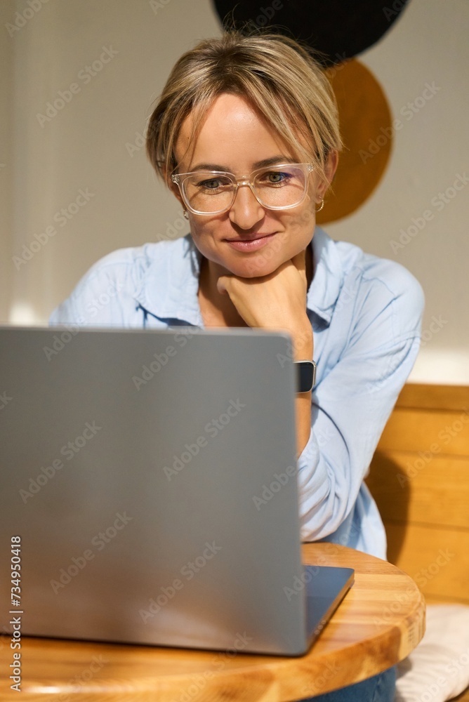 Woman sitting at cafe table and working on laptop computer. Female surfing internet on laptop using cafe wifi. High quality photo Woman sitting at cafe table and working on laptop computer. Female surfing internet on laptop using cafe wifi. High quality photo