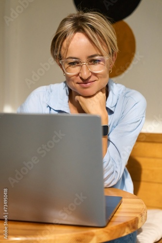 Woman sitting at cafe table and working on laptop computer. Female surfing internet on laptop using cafe wifi. High quality photo