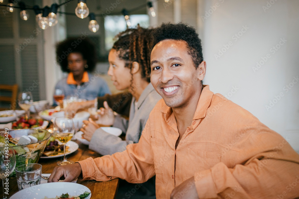 Portrait of smiling man sitting at dining table during dinner party in patio Portrait of smiling man sitting at dining table during dinner party in patio