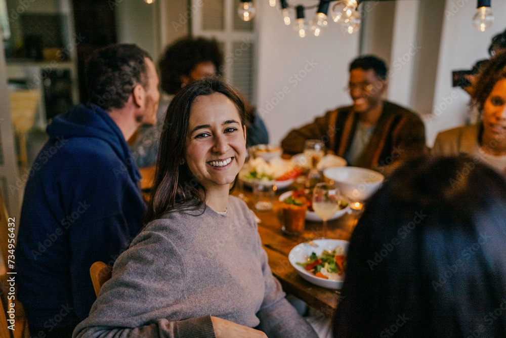 Portrait of smiling young woman sitting with friends at dining table Portrait of smiling young woman sitting with friends at dining table