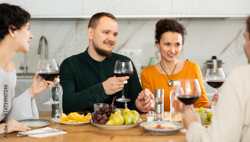 Group of happy celebrating holiday drinking and chatting at table at home
