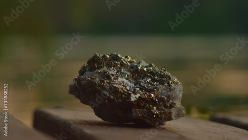 Close-up, pyrite crystal lying on a wooden pier against the background of the river