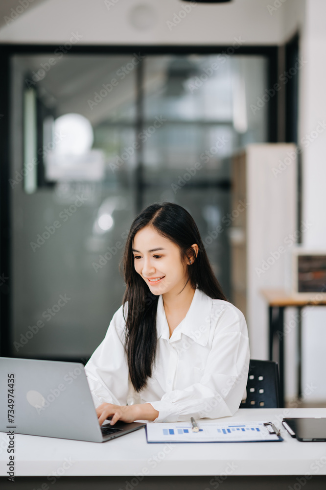 Beautiful Asian business woman typing laptop and tablet Placed at the table at office.. Beautiful Asian business woman typing laptop and tablet Placed at the table at office..