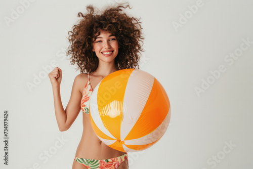 Funny young happy woman in swimsuit having fun holding inflatable ball and going on summer holiday trip standing on white studio background. Vacation tour and travel concept.