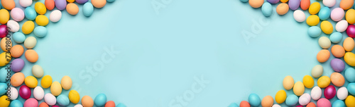 Multi-colored Easter eggs on a blue background, top view flat lay. Frame of decorative holiday eggs, space for text. Easter background, spring, layout for design. Long banner