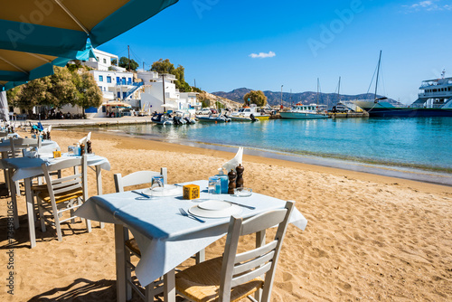 Greek tavern restaurant with tables on beach in Kimolos port, Kimolos island, Cyclades, Greece