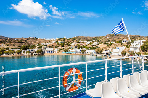 Deck of ferry with Greek flag leaving Milos island and sailing to Kimolos isl...