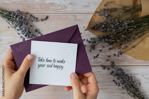 TAKE TIME TO MAKE YOUR SOUL HAPPY text on supportive message paper note reminder from green envelope. Flat lay composition dry lavender flowers. Concept of inner happiness, slowing-down digital detox  photo