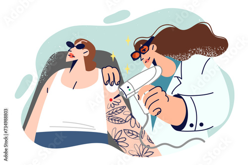 Woman undergoing laser tattoo removal procedure, located near cosmetologist erasing tattoo from skin