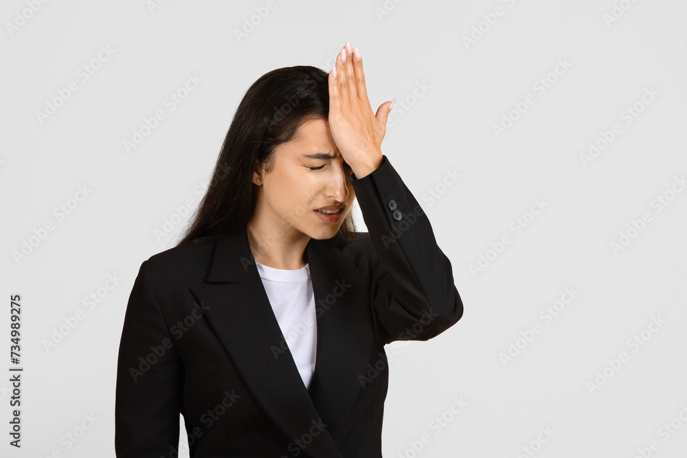 Regretful businesswoman with hand on forehead in forgetful moment