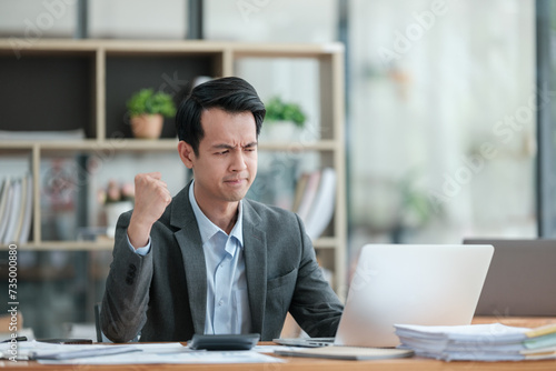 Young Businessman Using Laptop Computer in Modern Office. Manager Thinks About Successful Financial Ideas. Happy Man Smiling About Finding Problem Solving Solutions for Company.