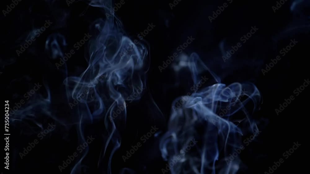 Thin Curls of Blue Smoke Rise Up, Fill Empty Space on a Black Background. Incense sticks. Abstract shapes. Texture. Beautiful clouds of smoke swirl. Floating fog, flowing smoke. Blurred motion. Light. Thin Curls of Blue Smoke Rise Up, Fill Empty Space on a Black Background. Incense sticks. Abstract shapes. Texture. Beautiful clouds of smoke swirl. Floating fog, flowing smoke. Blurred motion. Light.