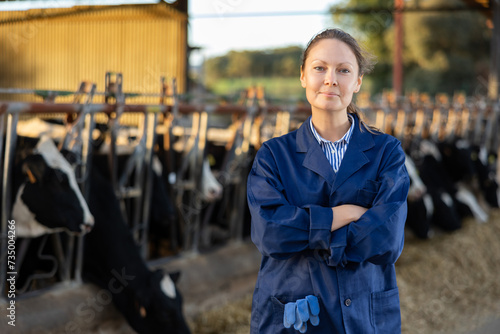 Cuadro en lienzo Portrait of smiling young woman working on livestock farm posing in outdoor cows