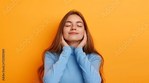 Retrato de uma bela jovem com os olhos fechados sobre um fundo amarelo photo