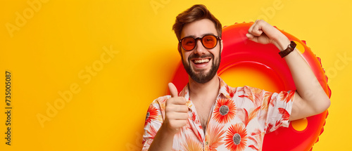 Jovem alegre em óculos de sol, mostrando os polegares sobre fundo amarelo photo
