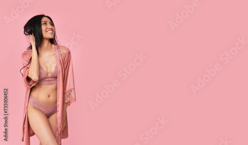 Beautiful brunette in pink lingerie and pajamas on a pink background.