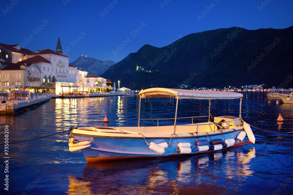 View of ancient picturesque city of Perast. Old medieval little town with red roofs and mountains on background of famous Kotor bay of Adriatic sea at blue hour. Travel in Montenegro.