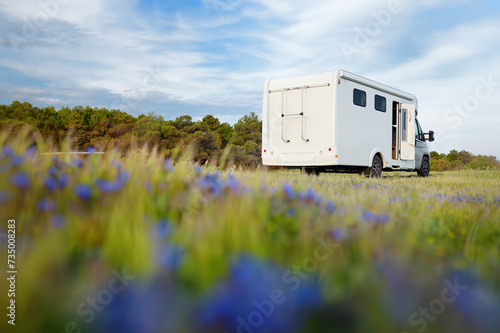 View of a large mobile home (design of van was changed during post processing ) parked in blooming meadow. Family vacation travel RV. Travel and adventure. Go everywhere