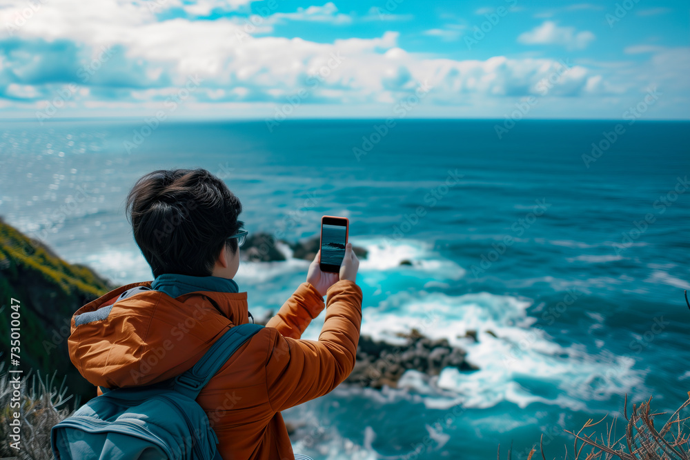 Obraz premium Person Capturing Breathtaking Ocean View with Smartphone from High Point