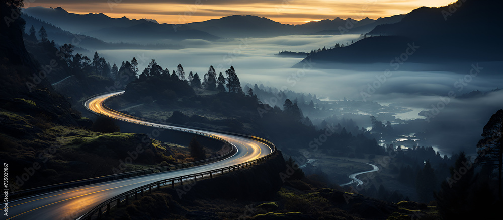 As dusk fell, lights and vehicle traces from cars and trucks could be seen circling along a mountain road between circular ravines. Scenic Dusk Drive: Lights and Trails on a Mountain Route - obrazy, fototapety, plakaty 