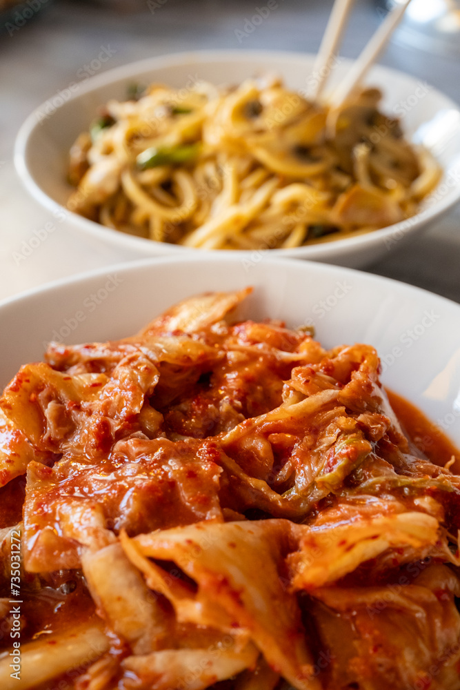 Noodles with mushrooms and vegetables and kimchi in white bowl close-up on gray background
Noodles with mushrooms and vegetables and kimchi in white bowl close-up on gray background