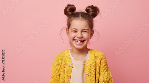 Retrato de uma menina sorridente com um suéter amarelo sobre um fundo rosa. photo