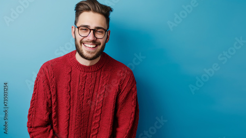 Retrato de um jovem sorridente, vestindo suéter isolado sobre fundo azul, olhando para a câmera photo