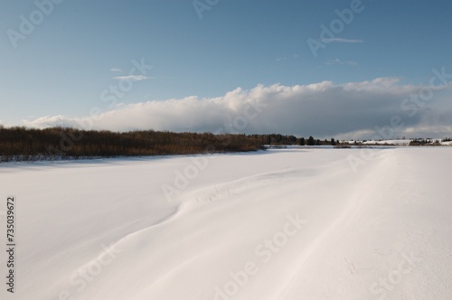 snow-covered river in spring, blue sky, sunny evening