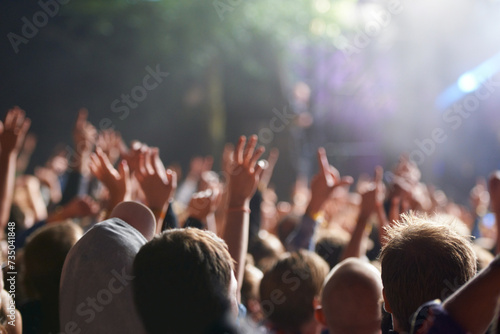 Hands, people and crowd at music festival with dancing for rock party at concert with stage lights, nightclub or dj. Group, entertainment and holiday techno in summer for new years, adventure or rave photo