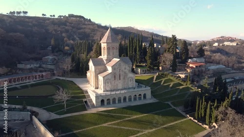 Scenic aerial view of monastic complex of Bodbe nunnery on hillside among tall Cypress trees with Church of St. Nino on sunny day, Sighnaghi, Georgia photo