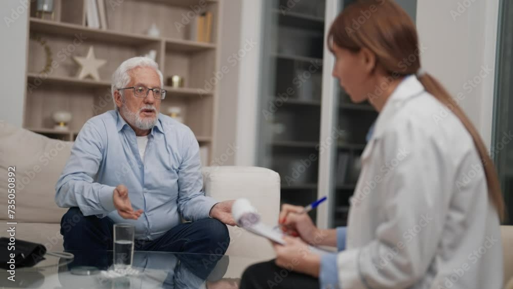 Senior man visits geriatric therapist. Old male sits on couch has medical examination in hospital. Checkup of pensioner concept. Woman doctor makes notes in medical card listening elderly patient. Senior man visits geriatric therapist. Old male sits on couch has medical examination in hospital. Checkup of pensioner concept. Woman doctor makes notes in medical card listening elderly patient.
