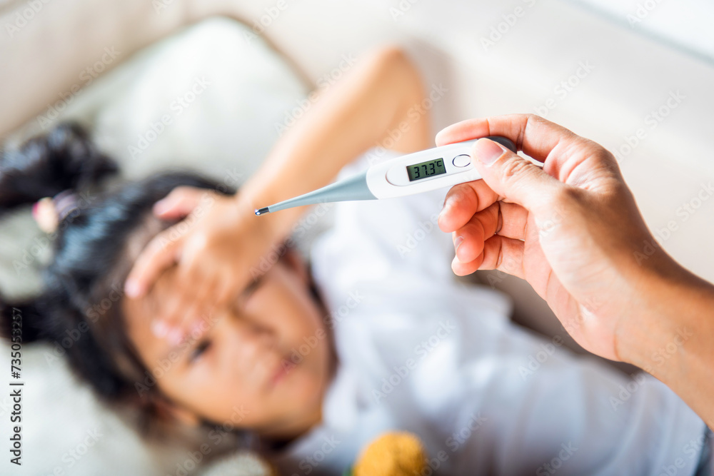© sorapop - Sick kid. Mother parent checking temperature of her sick daughter with digital thermometer in mouth, child laying in bed taking measuring her temperature for fever and illness, healthcare © sorapop - Sick kid. Mother parent checking temperature of her sick daughter with digital thermometer in mouth, child laying in bed taking measuring her temperature for fever and illness, healthcare