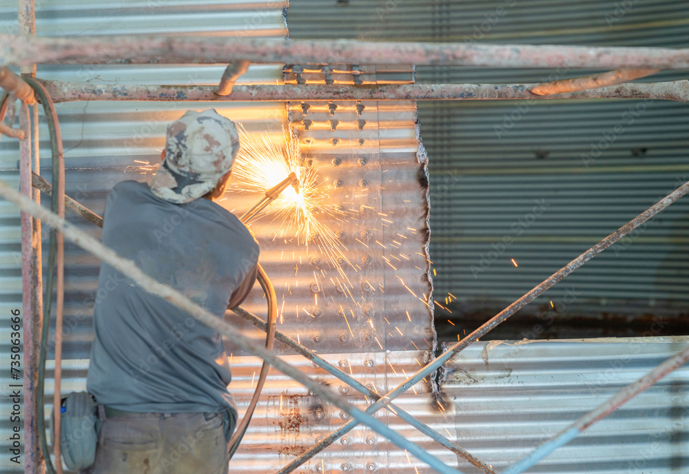 Fototapeta premium Worker cutting metal wall with metal cutting torch.
