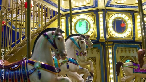 Old French carousel spins in a holiday park. Elephant horses on a traditional vintage fairground carousel. Carousel with horses in the evening at night with bright lights and flashes photo