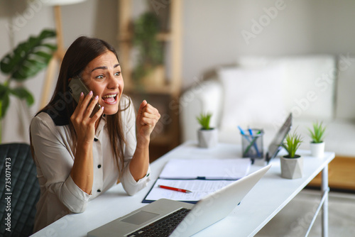 Young happy woman talking on the phone in the office