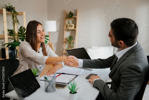 Young woman shakes hands with a business man at a business meeting
