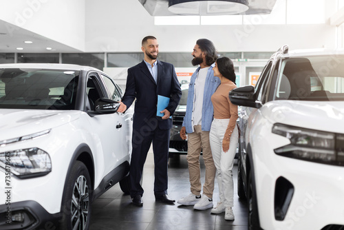 Successful millennial manager showing clients choice of vehicles at salon