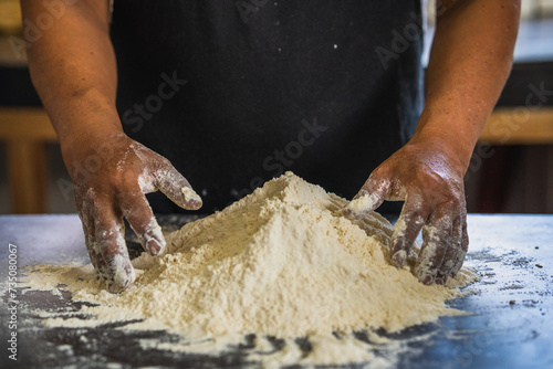 Baker's hands ready to knead a mound of flour, isolated on black background. prepares bread in the traditional way