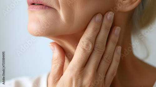 Beautiful middle-aged woman touches the soft smooth skin on her neck