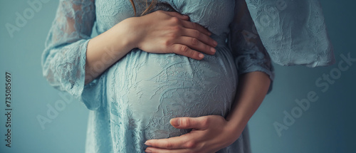Mulher grávida tocando sua barriga em fundo azul, closeup