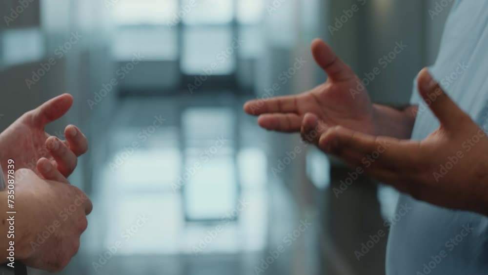 Close up shot of handshake of two male hospital workers standing in corridor and having discussion Close up shot of handshake of two male hospital workers standing in corridor and having discussion
