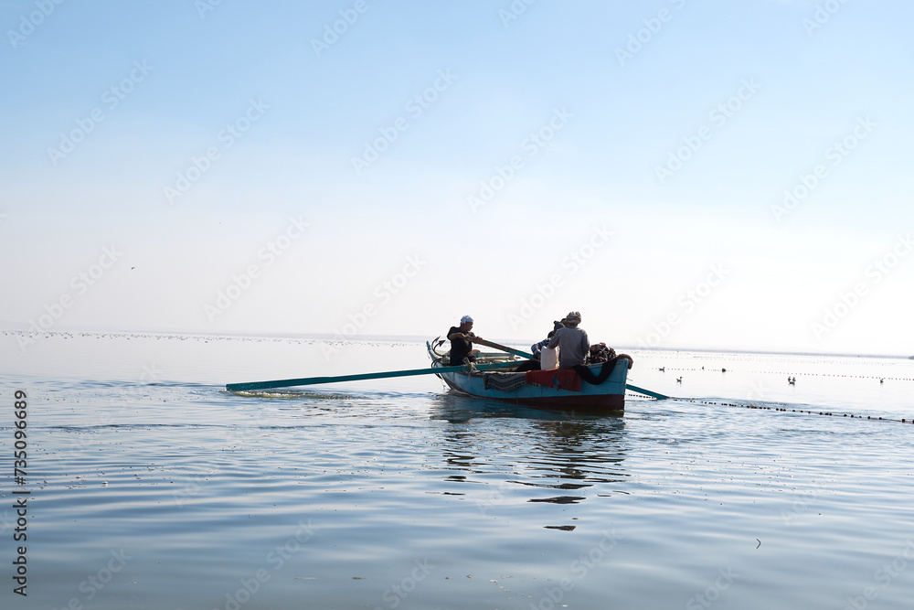 fisher man on sailboat fishing a fish on the lake in Fayoum Egypt.