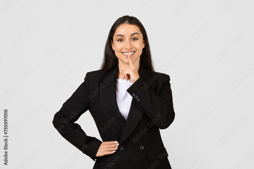 Confident young businesswoman with secret gesture Confident young businesswoman with secret gesture