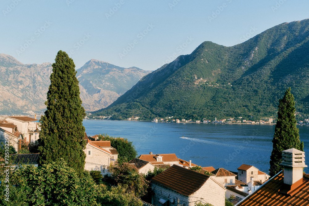 View over the red roofs of houses to the bay against the backdrop of green mountains