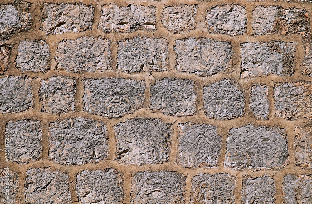Background, texture of a wall made of natural stone with thick seams sealed with cement
