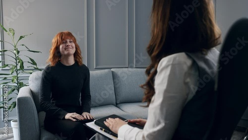Ukrainian civilian red hair woman having a psychotherapy session. A sad experience after military invasion. Young smiling girl coming to rehabilitation center to talk with therapist photo