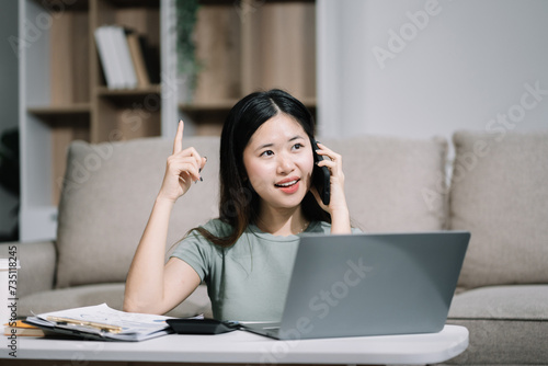 Consulent speaking to mobile cellphone at home office. women speak with remote clients using phone. Laptop on the desk. Home office smart working concept lifestyle.